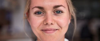 Close-up portret van een glimlachende jonge vrouw met blond haar