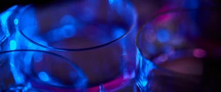 Close-up of petri dishes illuminated by vivid blue and purple light, creating a futuristic and scientific atmosphere with a focus on transparency and reflections.