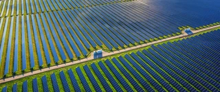 Aerial view of a large solar farm with rows of blue solar panels harnessing renewable energy.