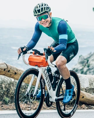 Jeffrey Lim cycles in a blue shirt and green shorts, showcasing an active lifestyle in a vibrant setting.