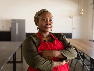 A woman crosses her arms in an empty kitchen